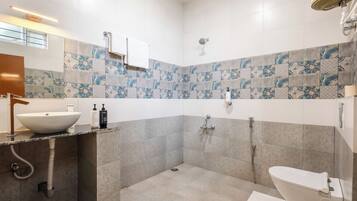 Un baño moderno con un lavamanos grande, un inodoro, una ducha y un espejo.