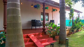 A covered outdoor area with a red staircase leading to a seating area with chairs and tables.