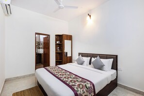 A bedroom with a bed, bedside tables, a wardrobe, a ceiling fan, and a wall-mounted light fixture. - Alaya Stays Eco Serenity 2-BHK With Pool (Doddaballapur)