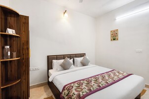 Un dormitorio con cama, armario de madera, lámpara de pared y un pequeño adorno.