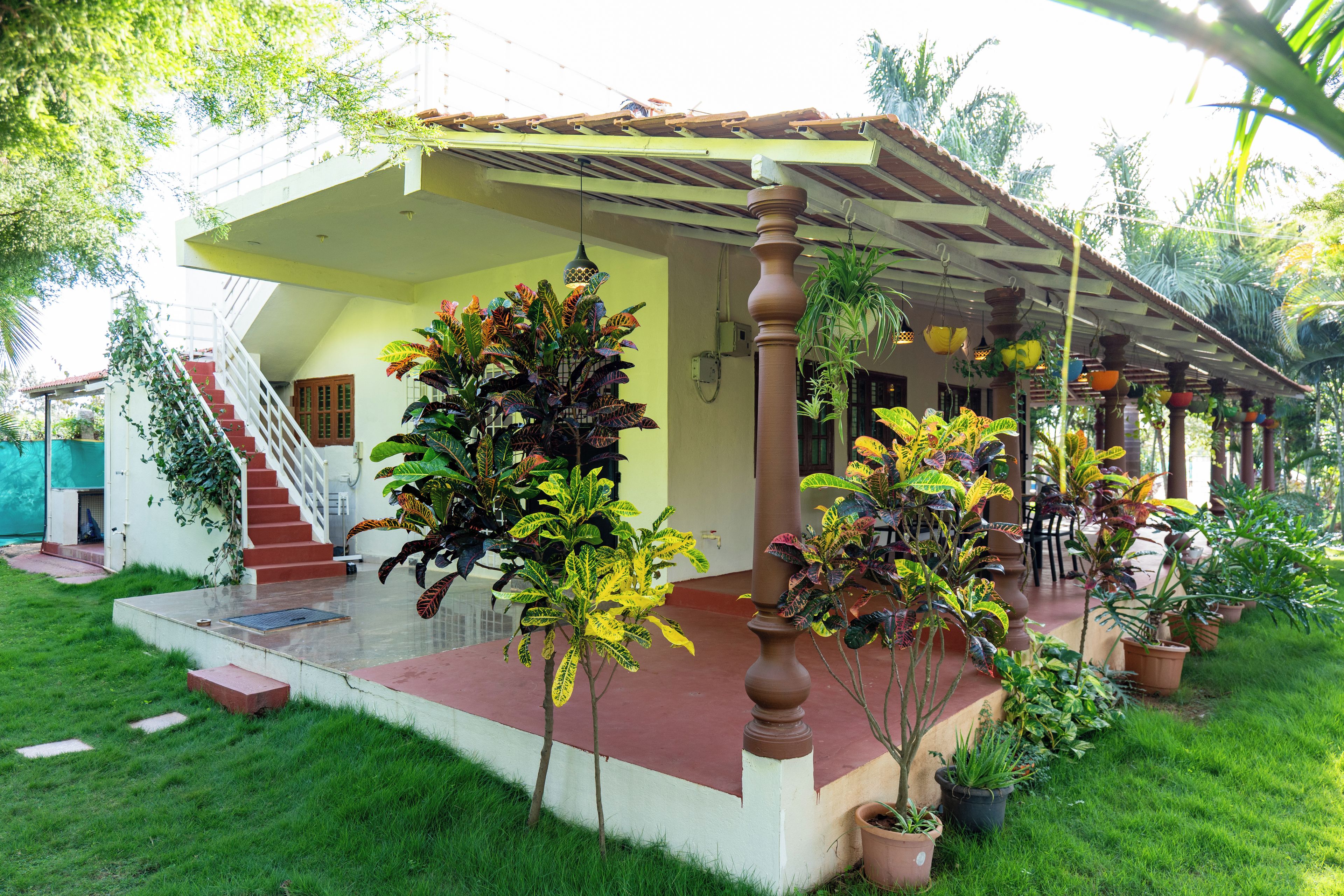 A house with a covered porch, a staircase, and potted plants.