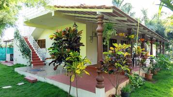 A house with a covered porch, a staircase, and potted plants.