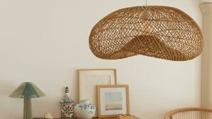 Un coin repas avec une table en bois, un luminaire suspendu en osier et un buffet en bois agrémenté d’objets décoratifs.