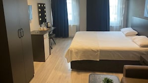 Ein Hotelzimmer mit Bett, Schreibtisch, Kleiderschrank und Spiegel.