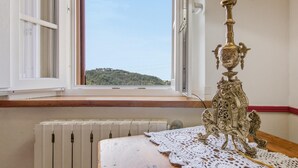 A room with a radiator, a table with a lace tablecloth, a lamp, and a window with an open shutter. - Former convent with private pool in Tuscany (Camaiore)