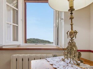 A room with a radiator, a table with a lace tablecloth, a lamp, and a window with an open shutter. - Former convent with private pool in Tuscany (Camaiore)