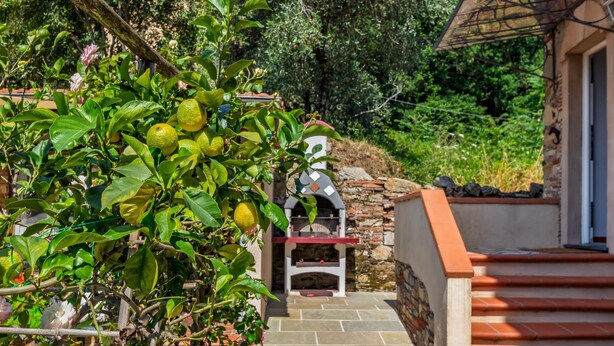 A stone pathway leading to a rustic outdoor seating area with a stone fireplace. - Former convent with private pool in Tuscany (Camaiore)