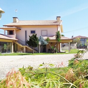 Ein zweistöckiges Haus mit Ziegeldach, einer Veranda und einer Auffahrt zum Eingang.