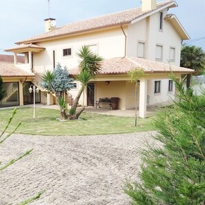 A two-story house with a tiled roof, a covered patio, and a paved driveway. - 1-Bedroom Apartment in Amares, Braga (September through June) (Barreiros)