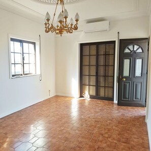 A room with a hexagonal tiled floor, a chandelier, a large window, and a door with a decorative design. - 1-Bedroom Apartment in Amares, Braga (September through June) (Barreiros)