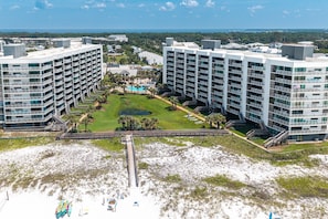 Een hoog hotel met meerdere balkons, een centrale binnenplaats met zwembad en een strandgedeelte op de voorgrond.