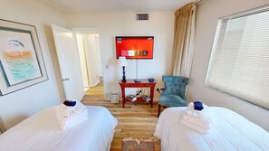 A hotel room with two beds, a TV, a desk, a chair, and a window with blinds. - Mainsail 152 2 Bedroom Condo (Miramar Beach)