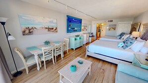 A hotel room with a bed, a desk, a chair, a TV, and a painting on the wall. - Islander Beach Resort 705 Condo (Fort Walton Beach)