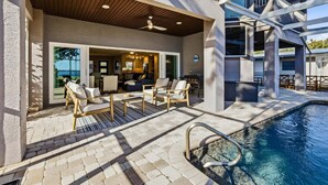 A modern outdoor living area with a pool, outdoor seating, and a covered patio. - Nst108 4 Bedroom Home (Punta Gorda)