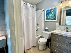 A bathroom with a white shower curtain, a toilet, a bathtub, and a sink with a mirror above it. - Gulfside Townhome 3 2 Bedroom Townhouse (Gulf Shores)
