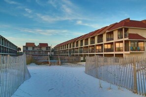 A row of motel buildings with multiple balconies and a sandy ground. - Gulfside Townhome 3 2 Bedroom Townhouse (Gulf Shores)