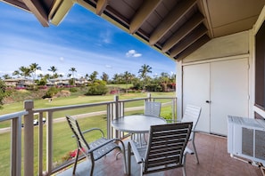 A balcony with a table and chairs, overlooking a golf course and residential buildings. - Wailea Grand Champion, #78 2 Bedroom Condo (Kihei)
