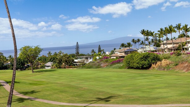 A golf course with a clear view of the ocean and a residential area with houses and palm trees. - Wailea Grand Champion, #78 2 Bedroom Condo (Kihei)