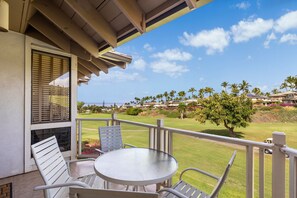A balcony with a table and chairs, overlooking a golf course and a residential area. - Wailea Grand Champion, #78 2 Bedroom Condo (Kihei)