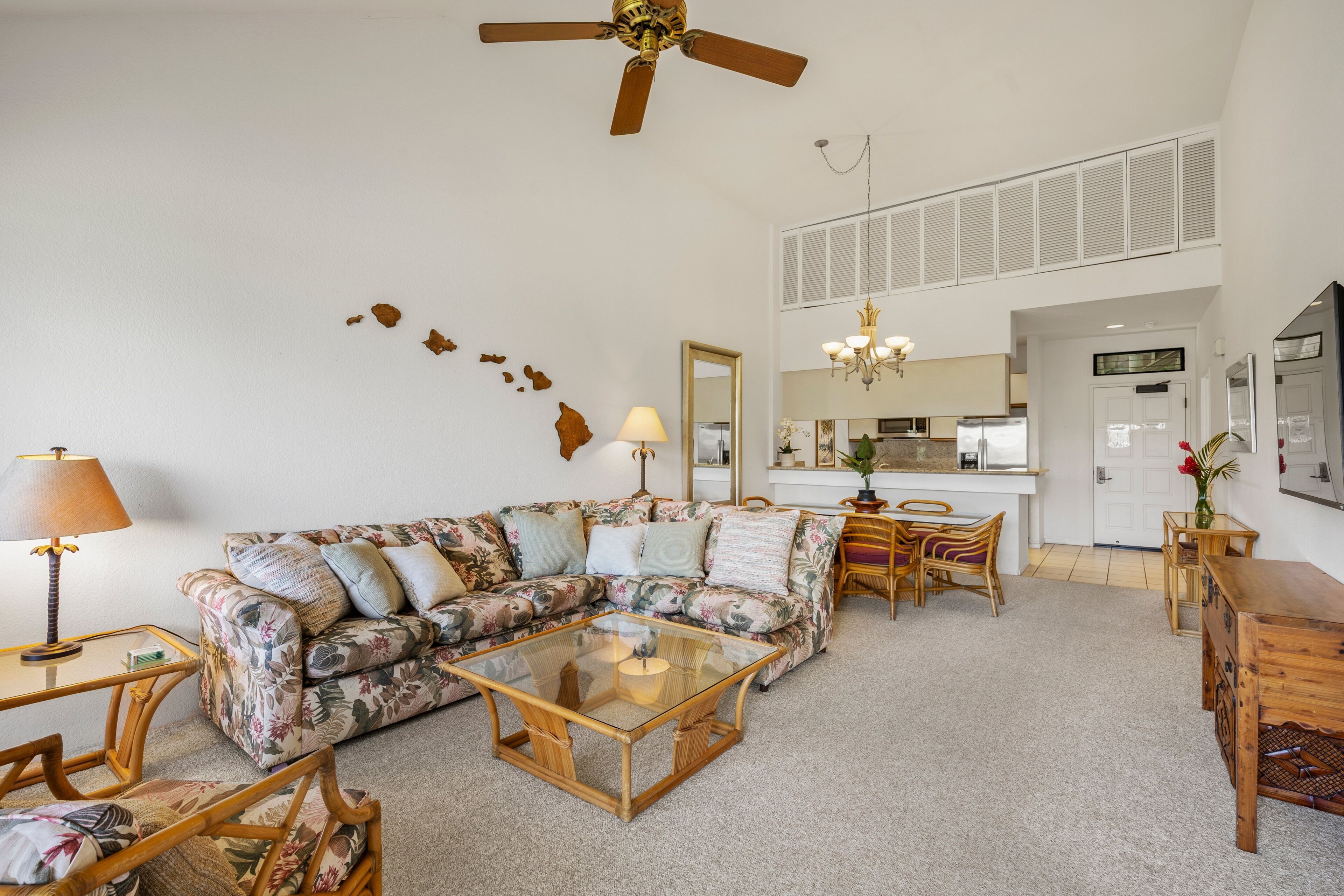 A living room with a sectional sofa, a glass coffee table, and a dining area with chairs.