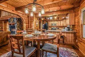 A wooden interior with a dining area, kitchen, and fireplace. - Rise And Shine 3 Bedroom Cabin (Gatlinburg)