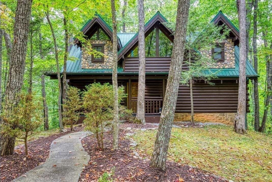 A log cabin with a stone foundation, multiple chimneys, and a porch.