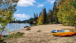 Une plage au bord du lac, avec des kayaks à disposition, et une vue dégagée sur le lac et la forêt.