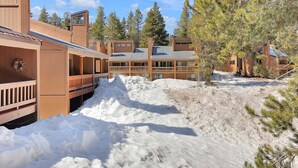 Un bâtiment de style cabane en bois, doté d’une terrasse et situé sur une pente enneigée.