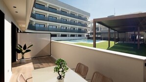Een modern hotelbalkon met uitzicht op een zwembad en omliggende gebouwen.
