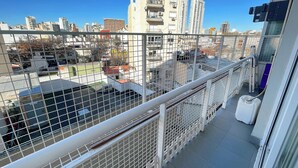 Un balcon doté d’une balustrade en métal, d’où l’on peut admirer un paysage urbain composé de nombreux bâtiments.