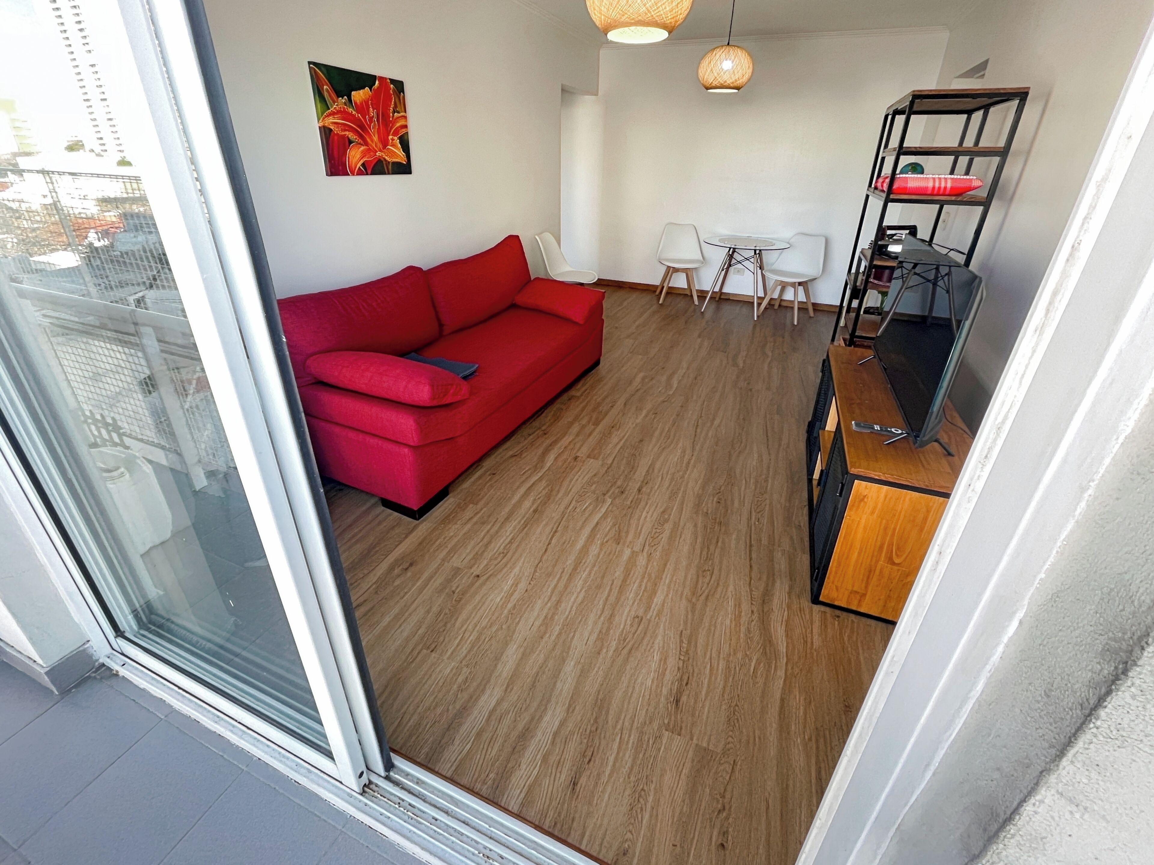 Un espace de vie moderne avec un canapé rouge, une table à manger avec des chaises et un plancher en bois.