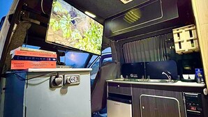 A compact kitchen with a refrigerator, a sink, and a window above the counter. - Campervan Tirana Leoventure (Tirana)
