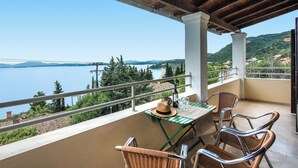 A balcony with wicker chairs, a table, and a bottle of wine. - Hotel Barbati - Poolside Gem with Sea views (Mparmpati)