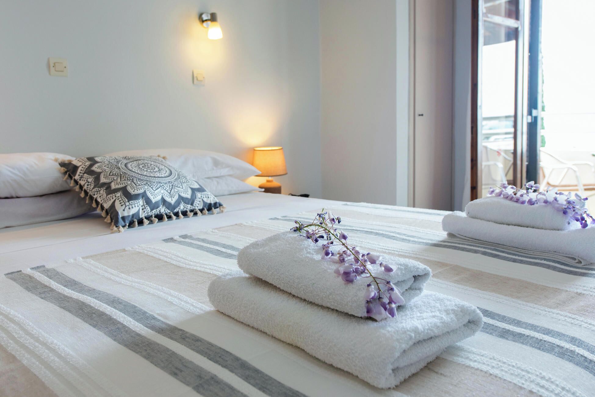 Ein Hotelzimmer mit Bett, Nachttischlampe und Blick ins Freie.