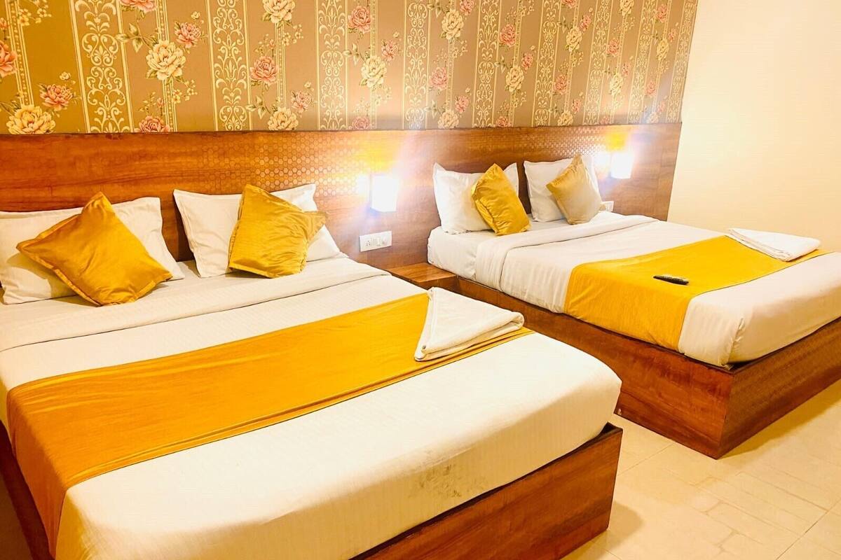 Two double beds with wooden headboards, white bedding, and yellow accents.