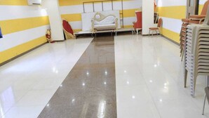 A hotel lobby with a long, shiny floor, a white sofa, and a row of stacked chairs. - The City Park Hotel  (Hyderabad)