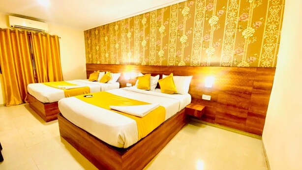 A hotel room with a large bed, two bedside tables, and a headboard with a floral pattern. - The City Park Hotel  (Hyderabad)