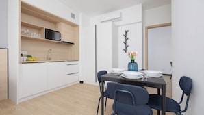 Eine moderne Küche mit weißen Schränken, einer integrierten Mikrowelle und einem Essbereich mit Tisch für vier Personen.