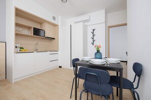 Ett modernt kök med vita skåp, en inbyggd mikrovågsugn och en matplats med ett bord som är dukat för fyra personer.