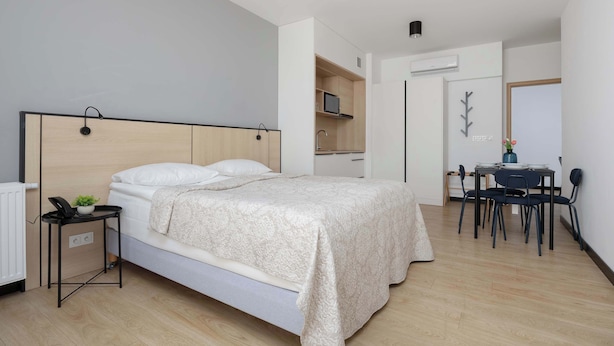 Ein modernes Schlafzimmer mit einem Bett, einem Nachttisch und einem kleinen Schreibtisch mit Stuhl.