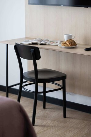 Ein modernes Zimmer mit einem Holztisch, einem schwarzen Stuhl, einer weißen Tasse und einem Teller mit einem Keks.