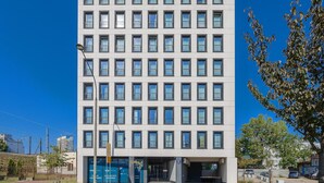 Un immeuble moderne à plusieurs étages, doté d’une façade uniforme, de grandes fenêtres et d’une entrée bien visible.