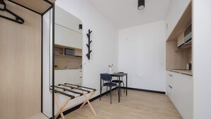 Une cuisine compacte avec un banc en bois, une petite table avec des chaises et un porte-manteau noir.