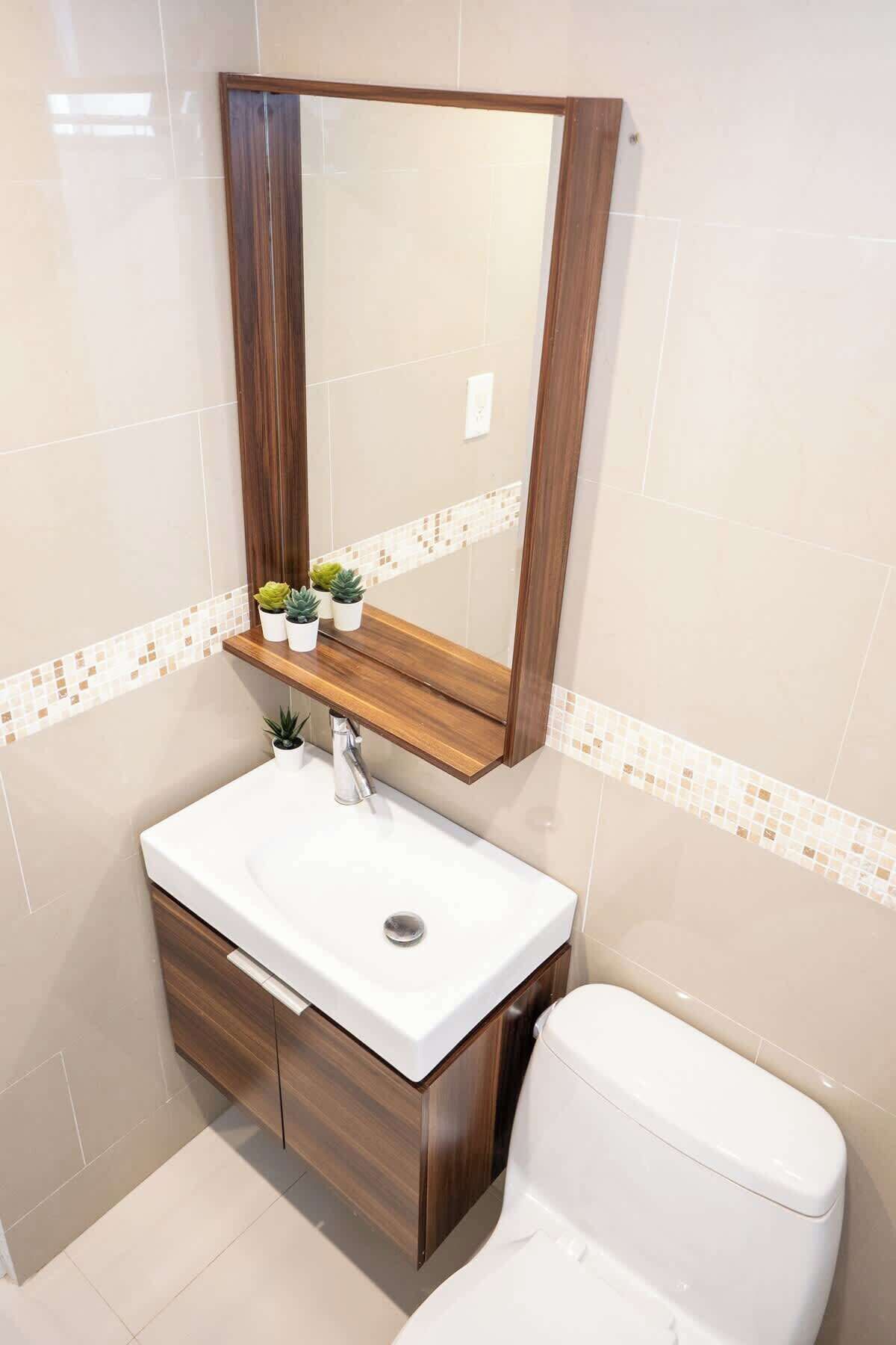 A bathroom with a white sink, wooden vanity, and a mirror above it.