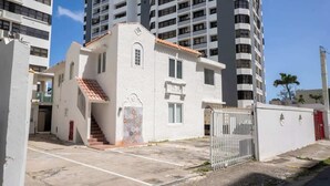 A building with a white facade, a red-tiled roof, and a gated entrance. - 3Bedroom Apt. Walking To The Beach C.2 (San Juan)