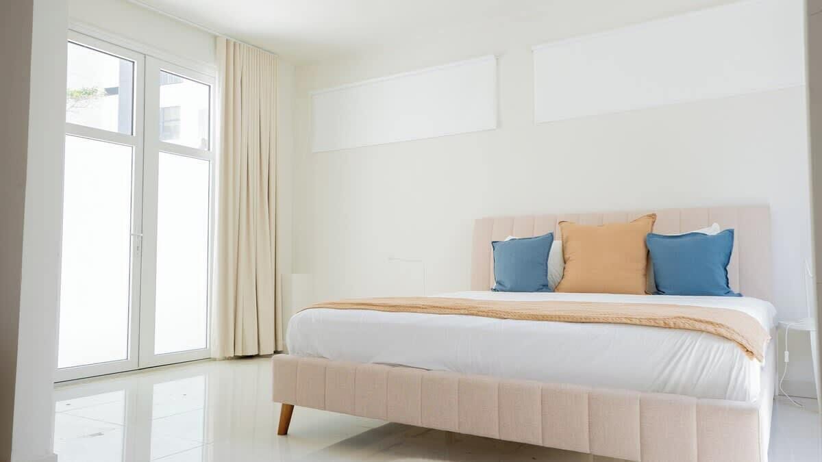 Un dormitorio con cama, cortinas y ventana.
