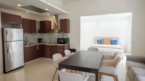 A modern kitchen with a refrigerator, microwave, and stove, a dining area with a table and chairs, and a bedroom with a bed and pillows. - 3Bedroom Apt. Walking To The Beach C.2 (San Juan)