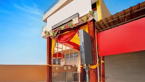 A building entrance with a red and yellow facade, a gated entrance, and a clear blue sky. - Classic Hotel Haveli inn (Meerut)