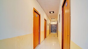 A hotel hallway with wooden doors, a tiled floor, and a patterned wall. - Classic Hotel Haveli inn (Meerut)