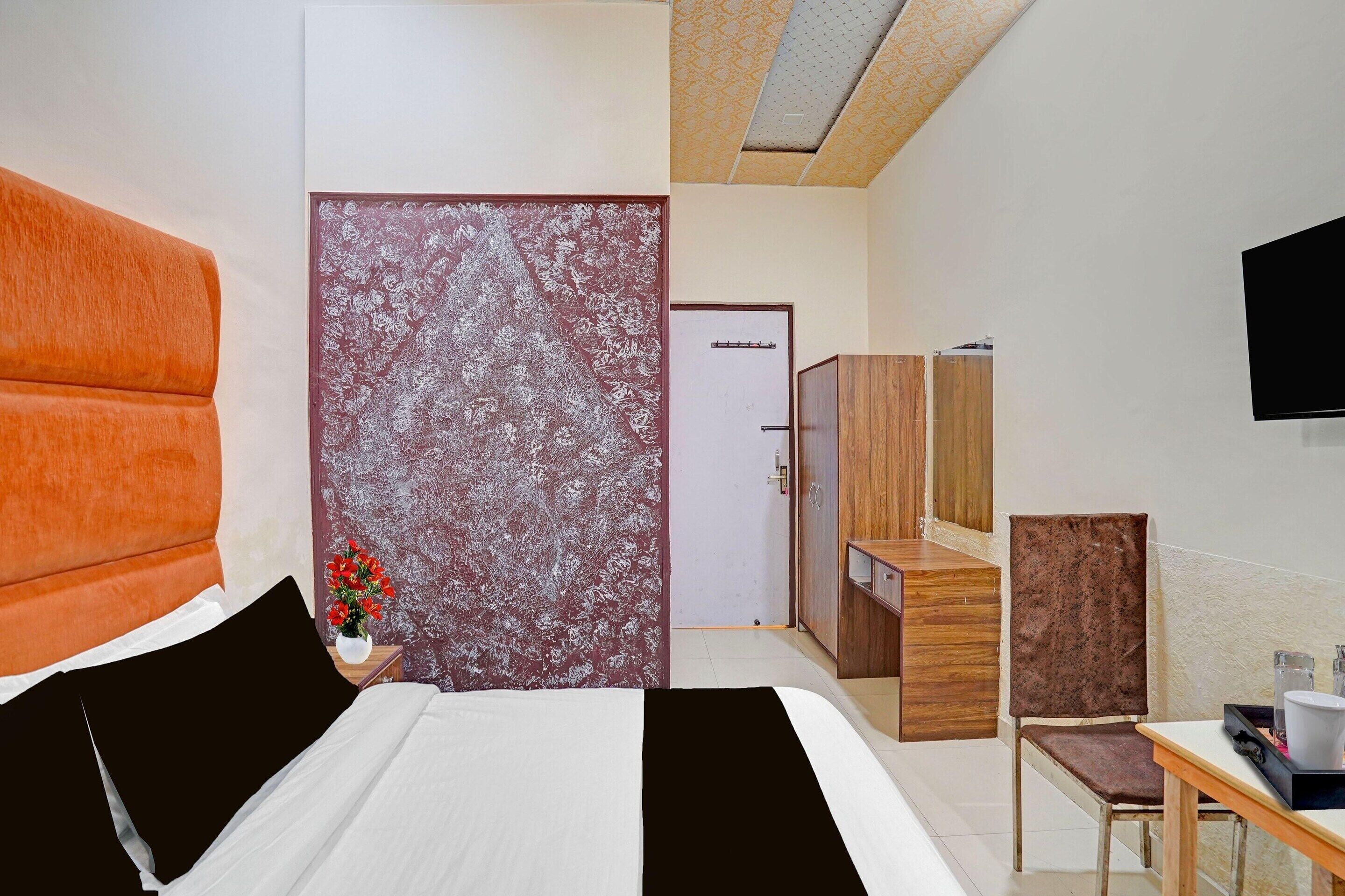 Een hotelkamer met een bed, een bureau, een stoel, een televisie en een deur.